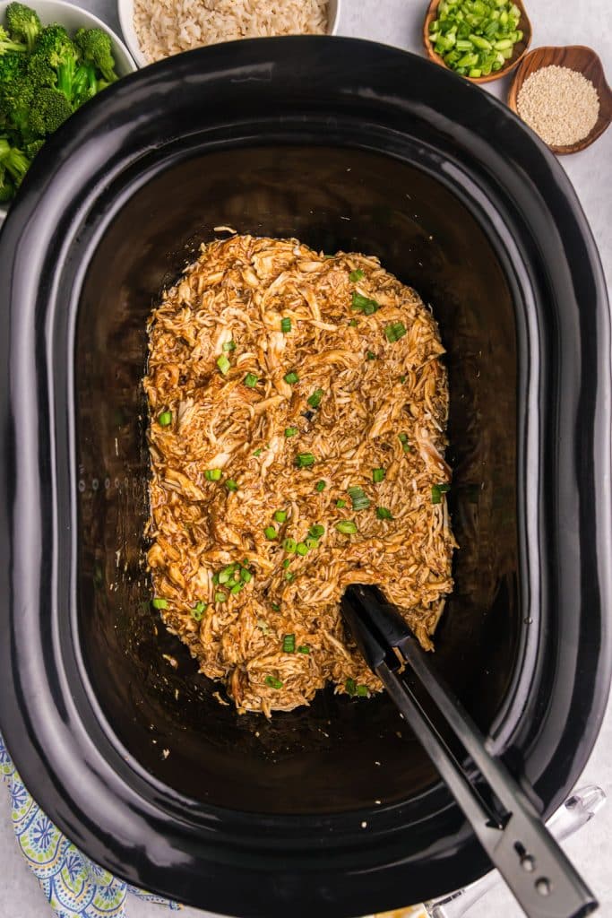 overhead shot of slow cooker honey teriyaki chicken in a black crockpot.