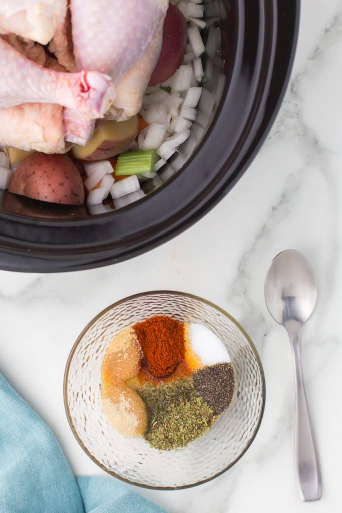 bowl of seasoning next to a crockpot.