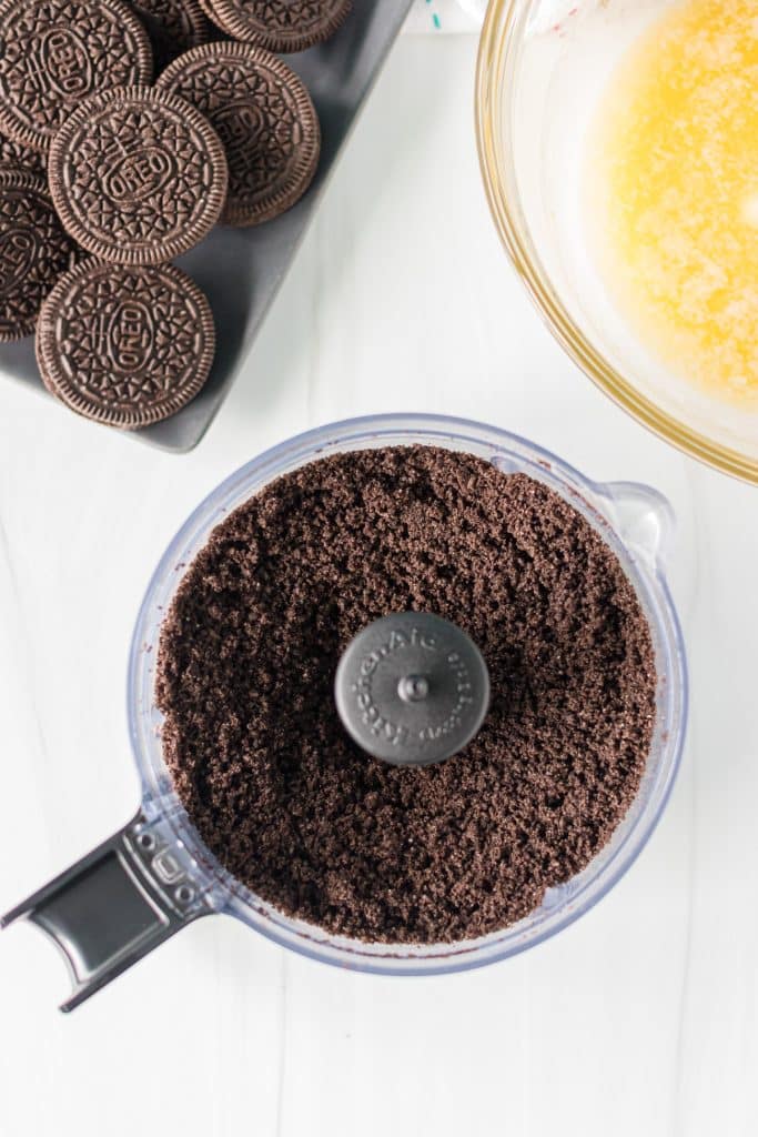 overhead shot of crushed oreo crumbs in a food processor.
