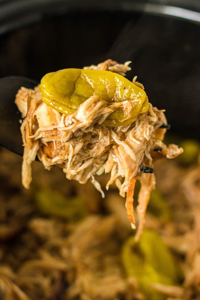 spoon scooping mississippi chicken from a crockpot.