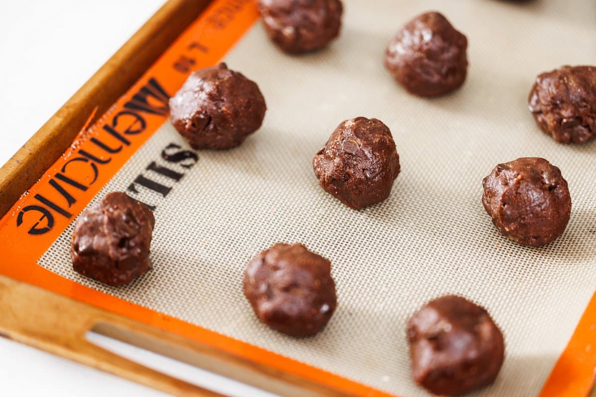 Rolled balls of cookie dough on a prepared baking sheet.