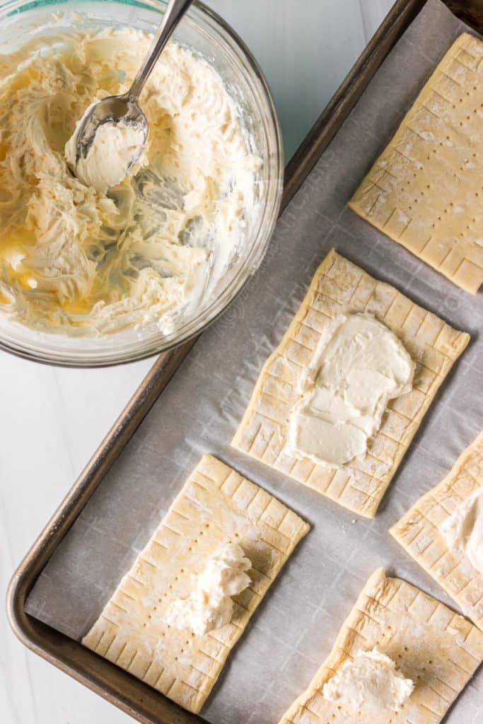 overhead shot of cream cheese filling spread onto puff pastry rectangles.