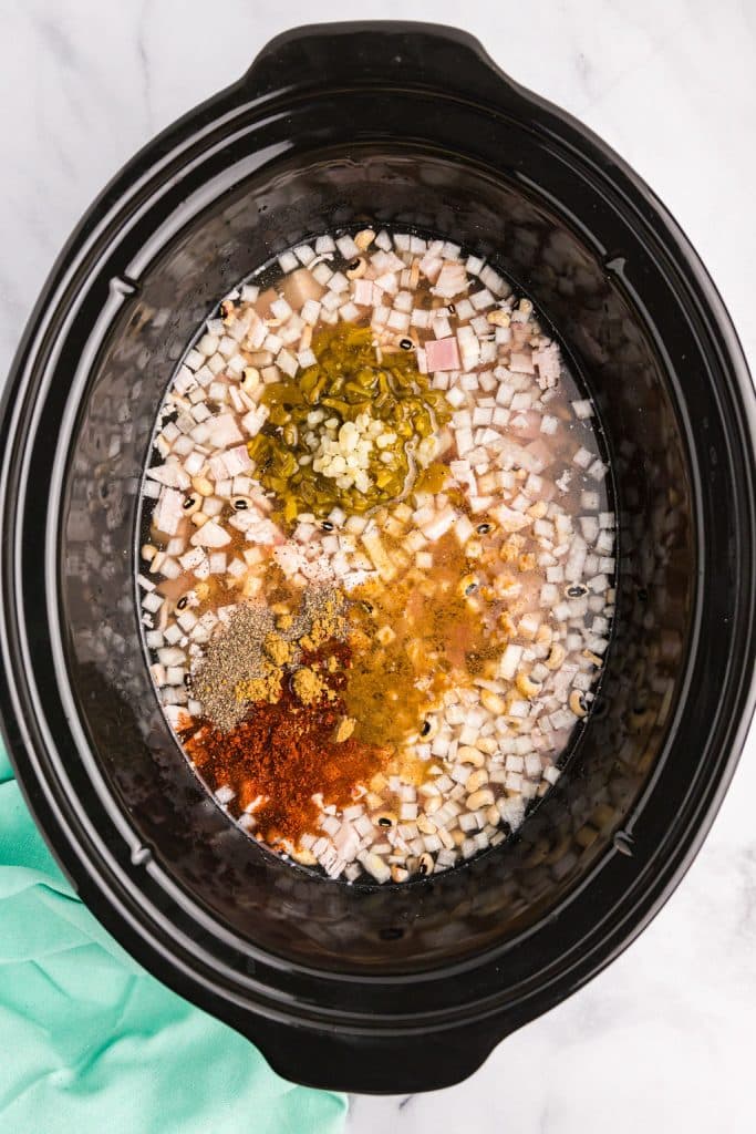 overhead shot of spices and peas in a crockpot.