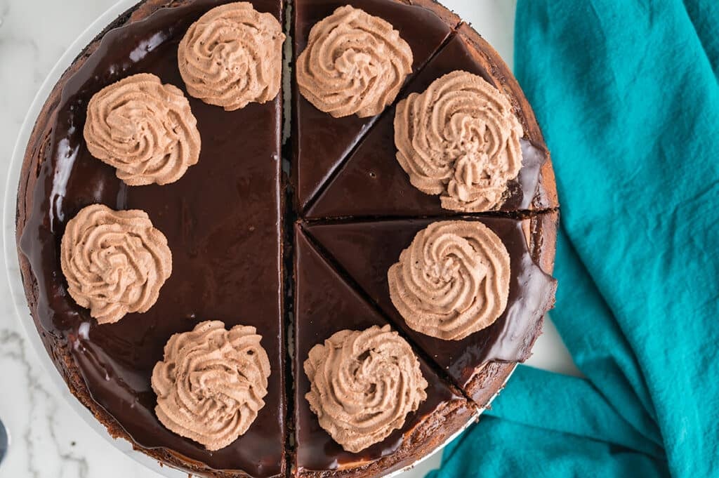overhead shot of chocolate whipped cream piped onto a chocolate cheesecake.