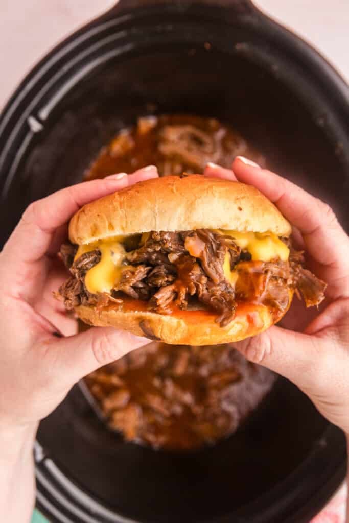 hands holding a copycat beef n cheddar sandwich.