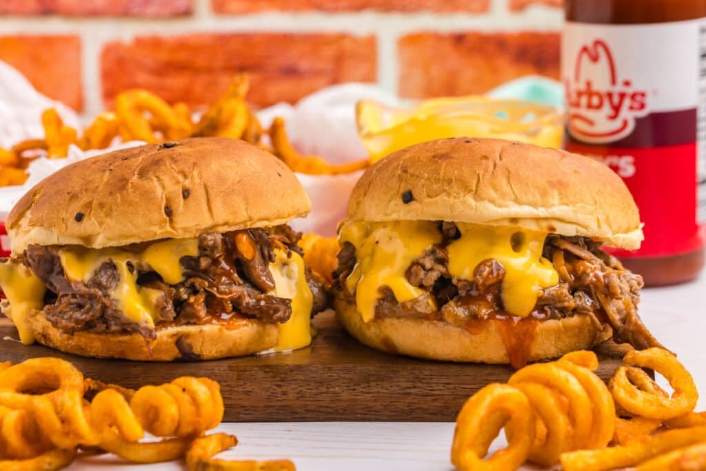 two copycat arby's beef n cheddar sandwiches with curly fries.