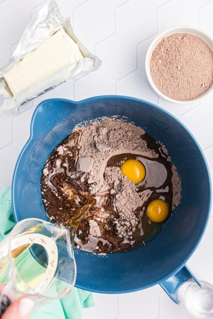 water pouring into a mixing bowl of brownie mix.