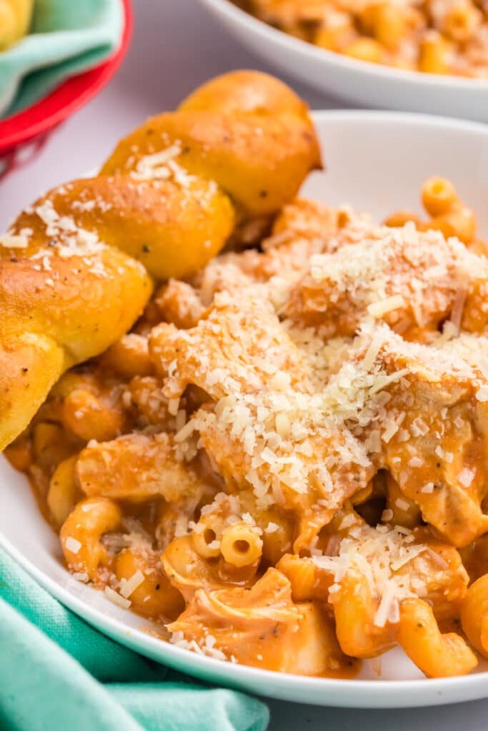 plate of creamy chicken pasta with a breadstick.