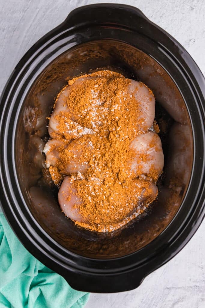 taco seasoning on chicken breasts in a crockpot.