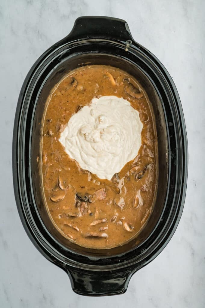 sour cream gravy mixing into a crockpot.