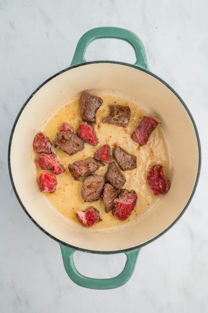 beef cubes in a pot searing.