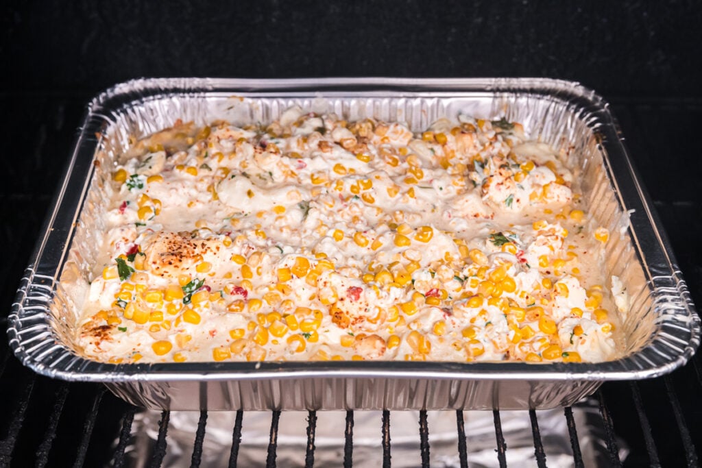 corn dip in a pan in a smoker.