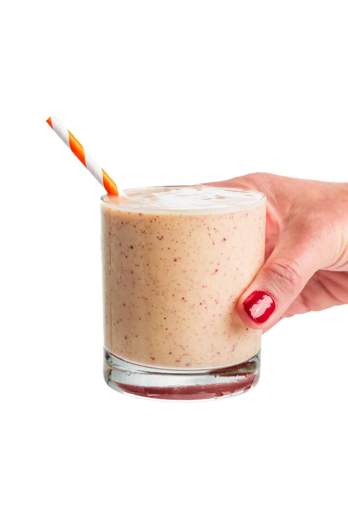 Holding a peach protein smoothie.