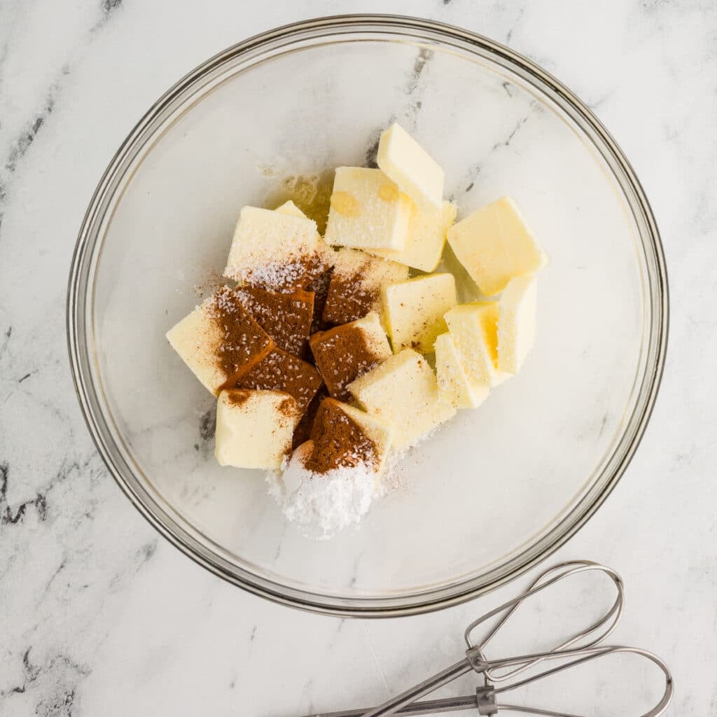 overhead shot of butter, cinnamon, and powdered sugar in a mixing bowl.