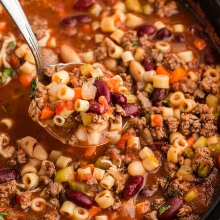 ladle scooping pasta fagioli from a slow cooker.