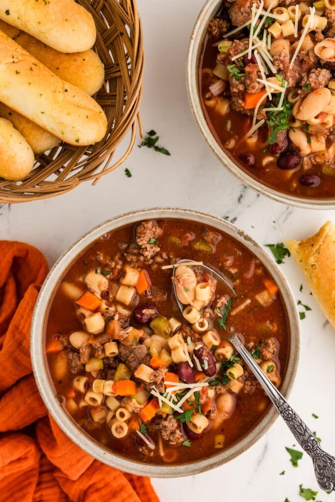 two bowls of pasta fagioli with breadsticks.