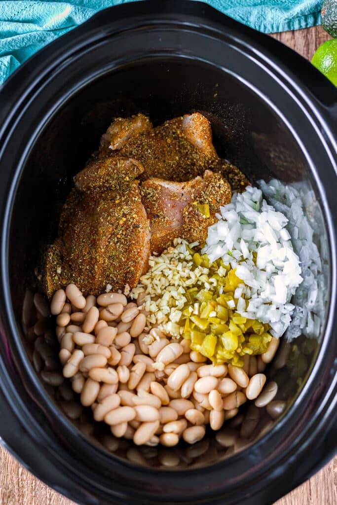 overhead shot of chicken, beans, onion, chiles in a crockpot.
