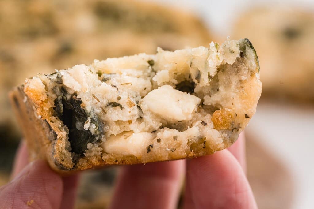 hand holding a slice of spinach feta bread with butter.