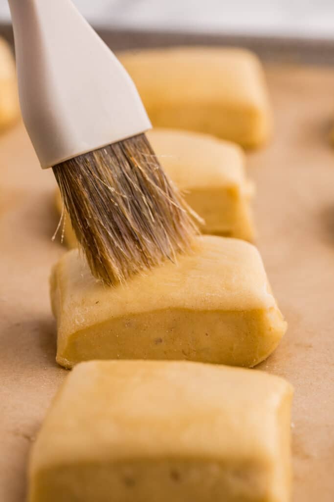 pastry brush brushing butter on a roll before baking.