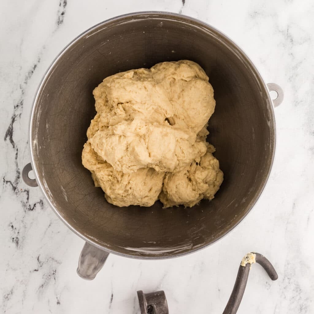 dough in a mixing bowl next to a dough hook.