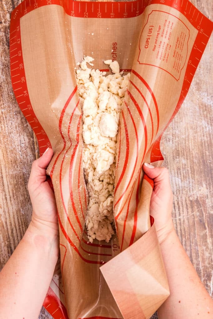 silicone mat pressing together crumbly pie dough.