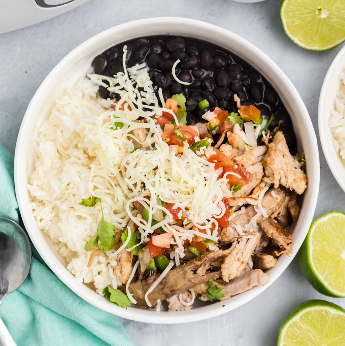 overhead shot of carnitas rice bowl with cheese, black beans, and pico de gallo.