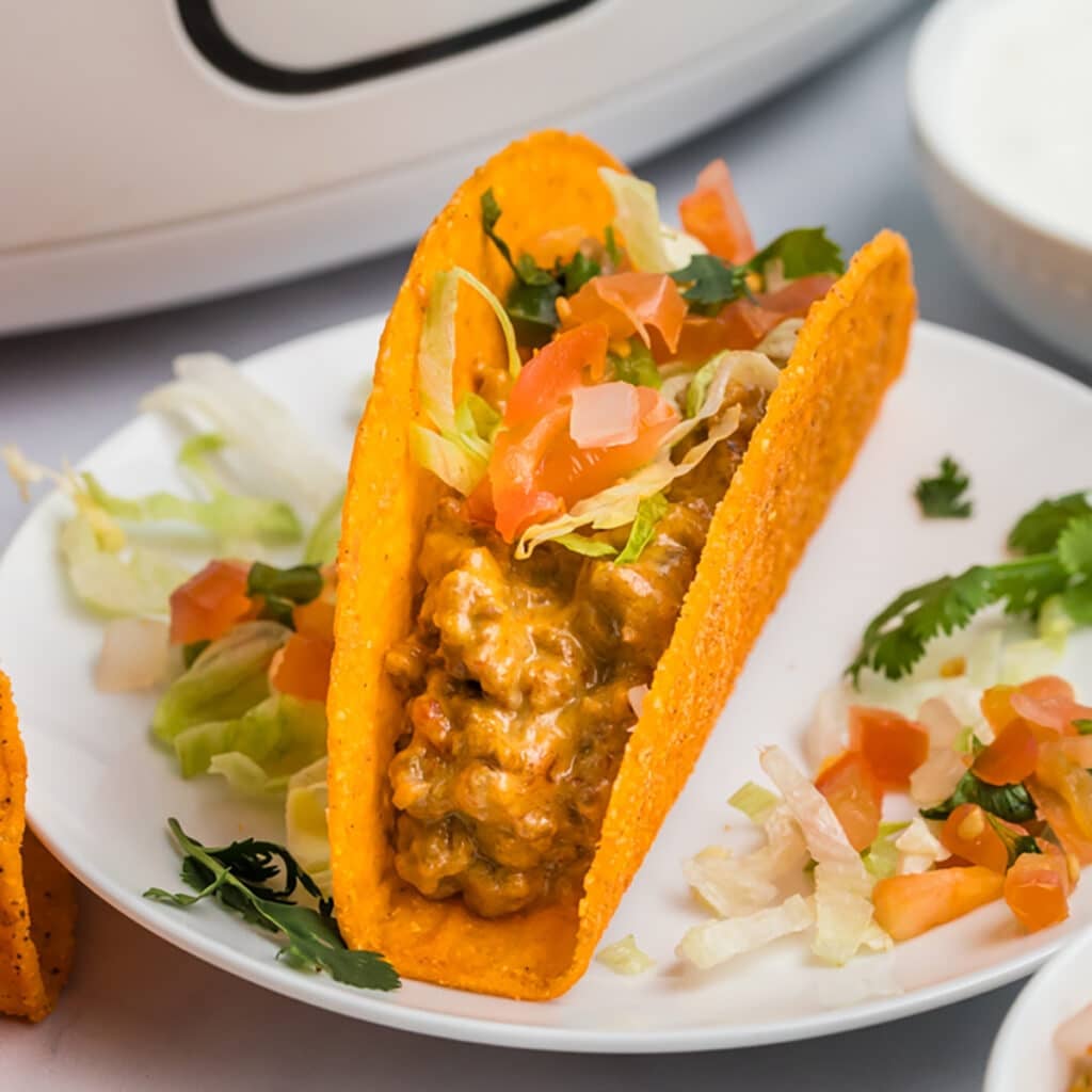 a rotel taco in a nacho cheese shell on a plate.