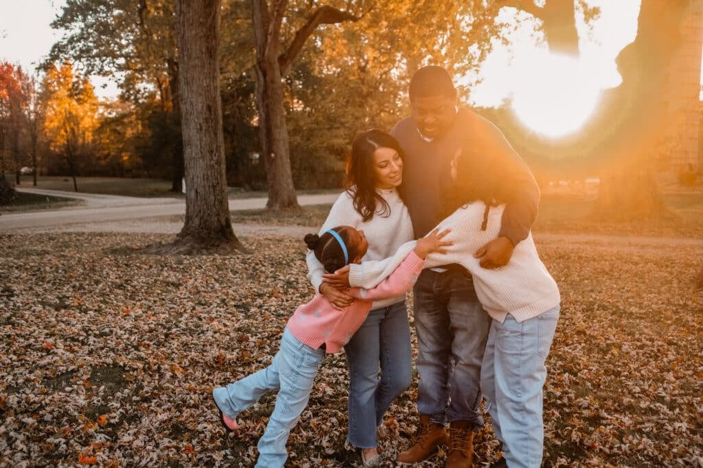family of 4 hugging in golden hour light.