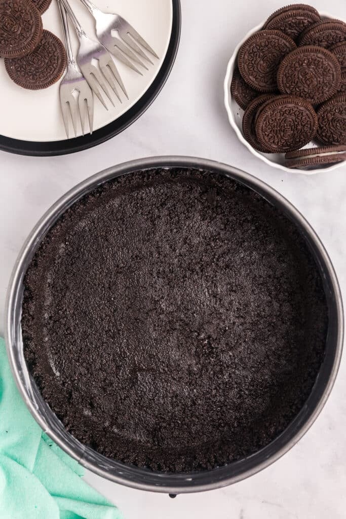 overhead shot of an oreo crust in a springform pan.