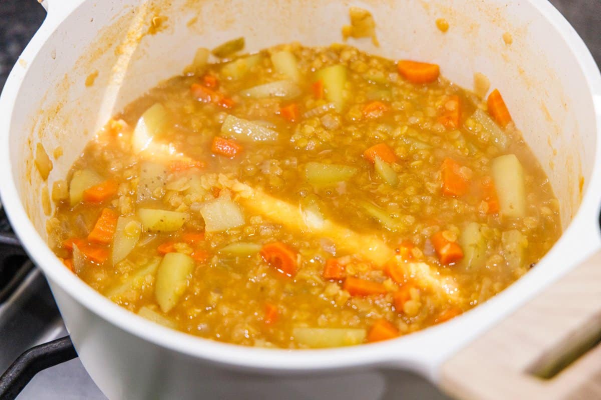 Chicken broth added to lentils and veggies in a pot.