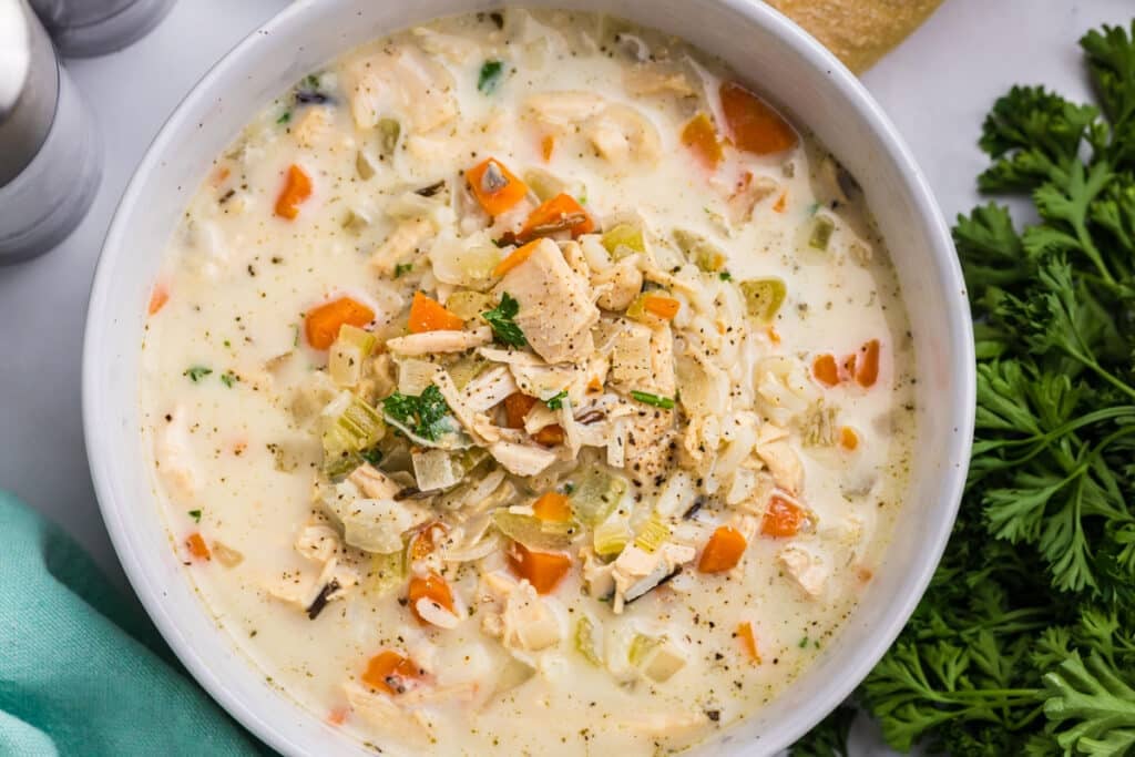 A bowl of creamy turkey rice soup with vegetables.