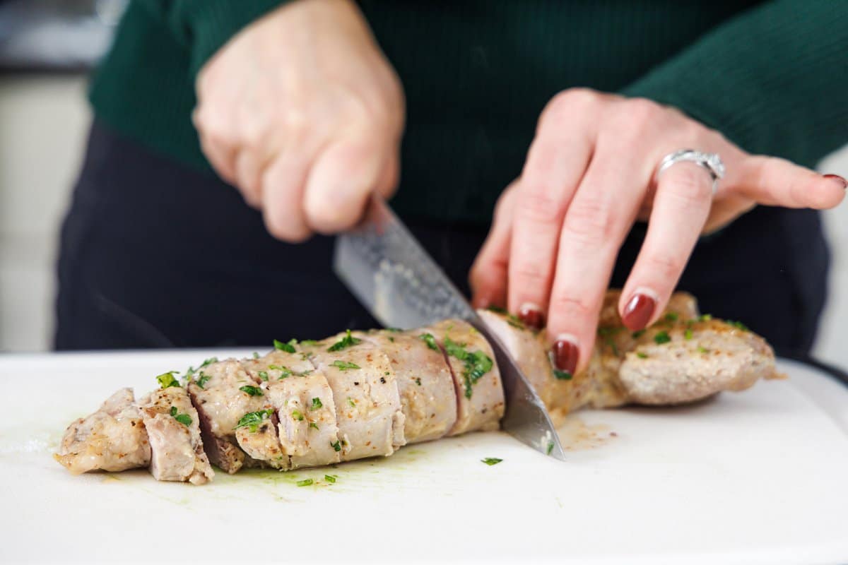 Cutting cooked pork tenderloin into small pieces.