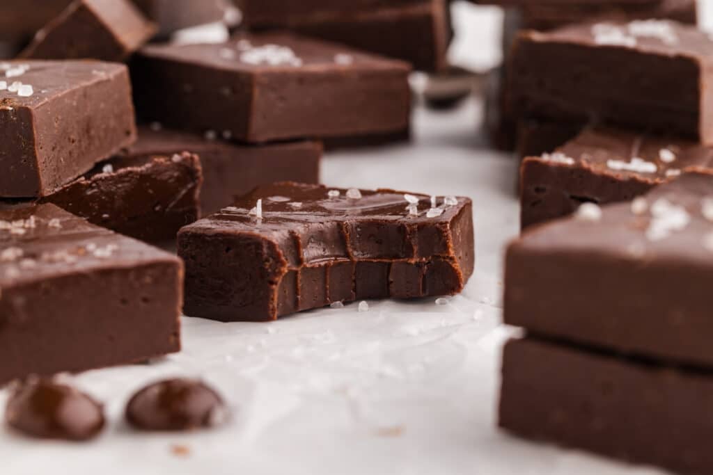 Dark chocolate fudge with flaky salt, one piece with a bite.