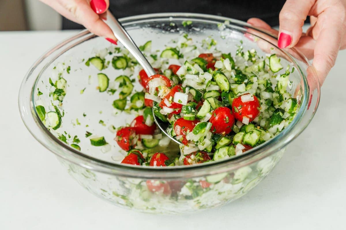Mixing all ingredients for pico de gallo in a large glass bowl.