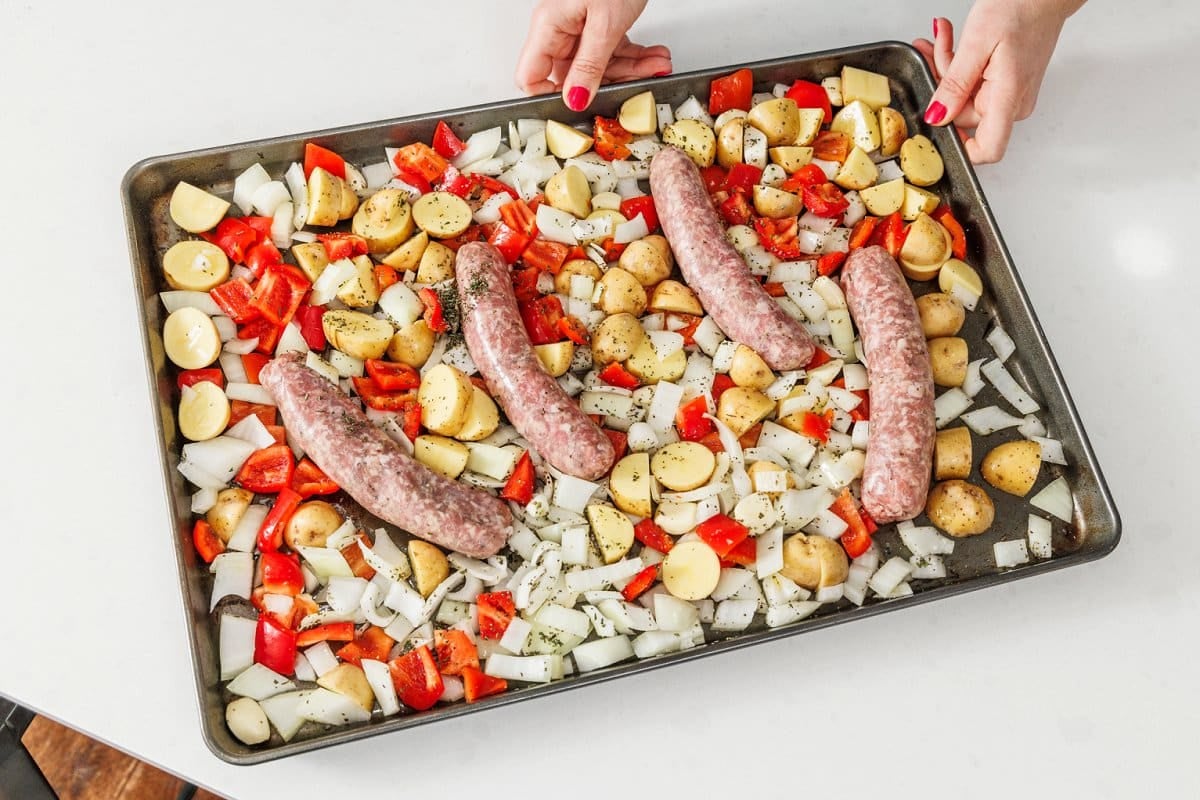 Cut vegetables and sausage on a sheet pan.
