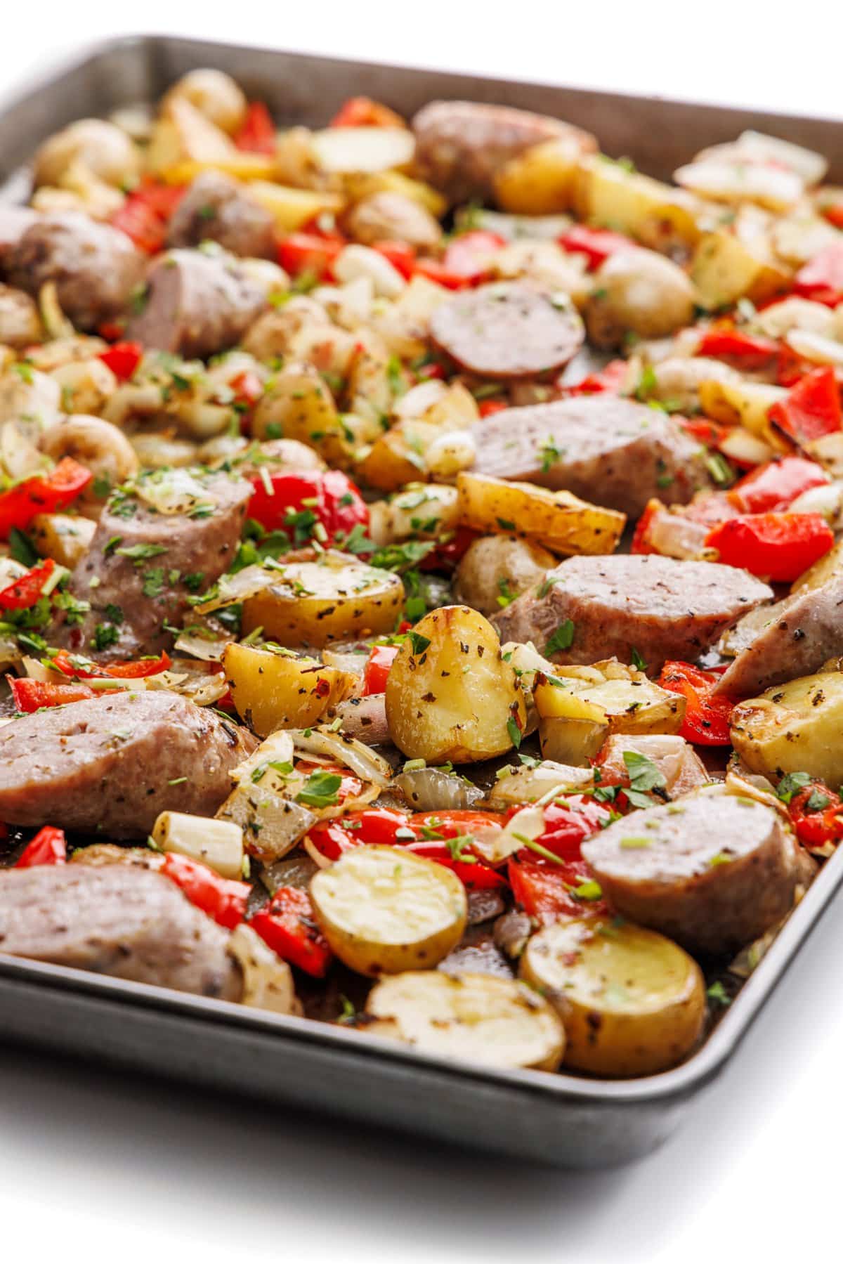 Sheet pan sausage, peppers, and potatoes with fresh parsley on top.