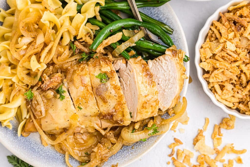 Sliced French onion chicken with noodles and green beans.