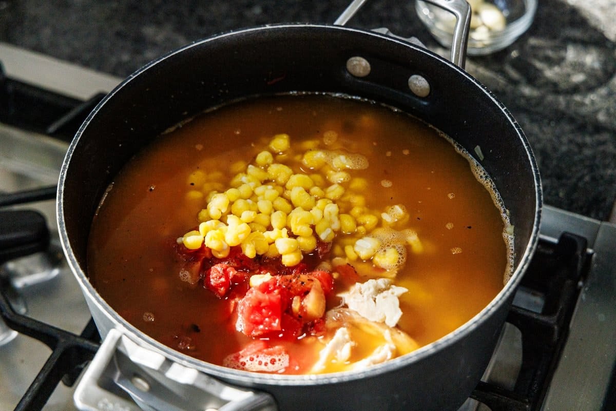 Hominy and diced tomatoes sitting atop soup.