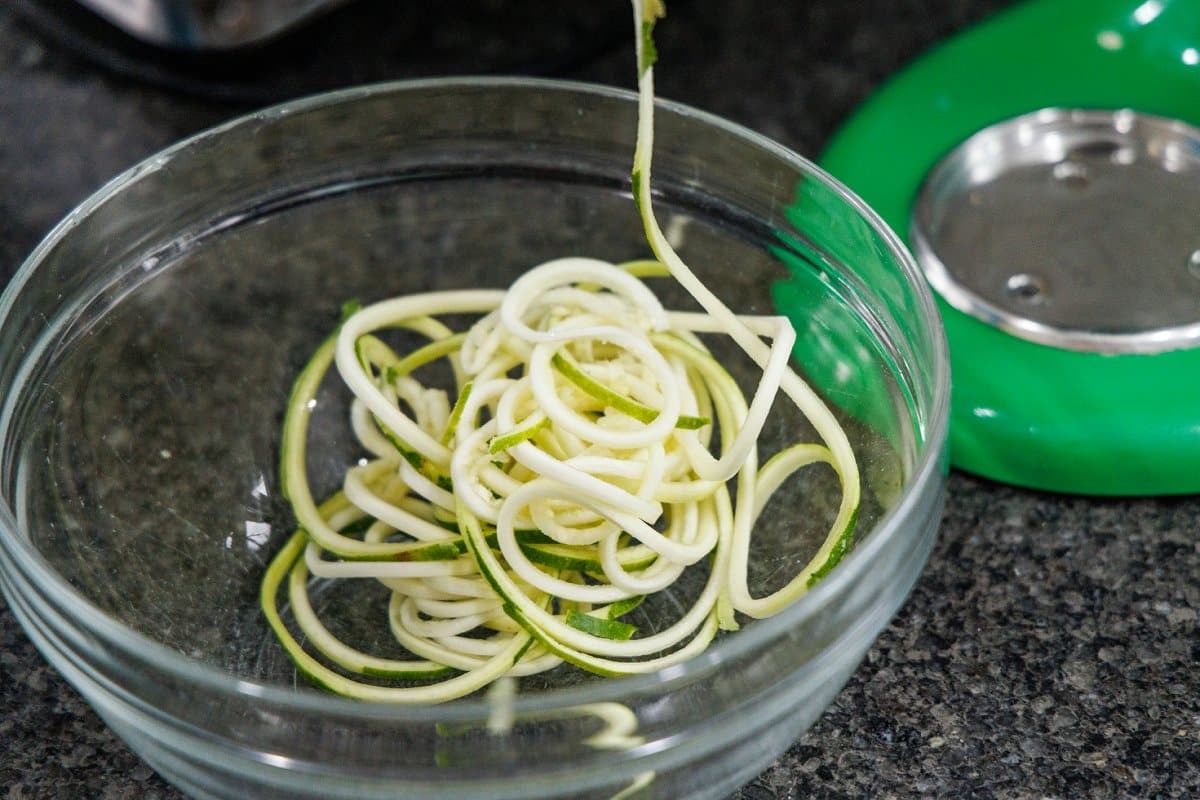 Making zucchini noodles with a spiralizer on a stand mixer.