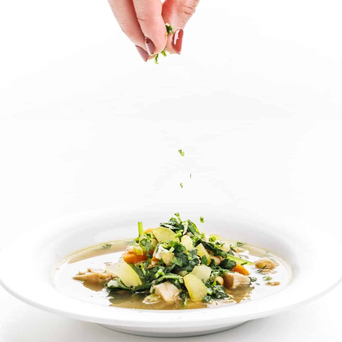 Garnishing easy chicken soup with greens.