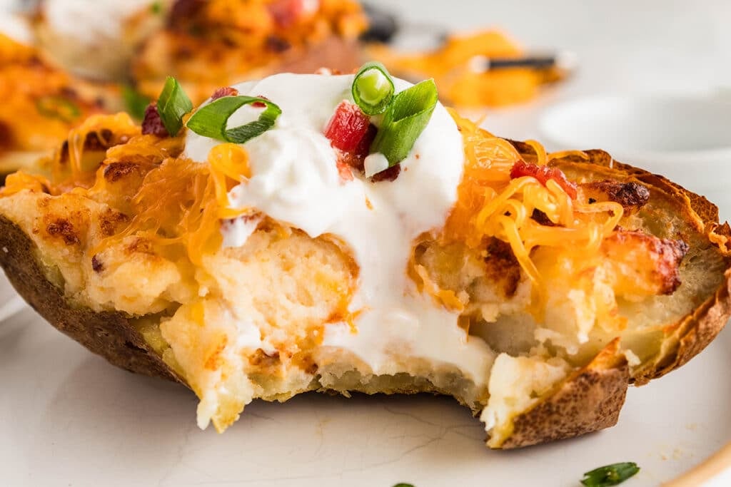side view of a twice baked potato topped with sour cream and chives.