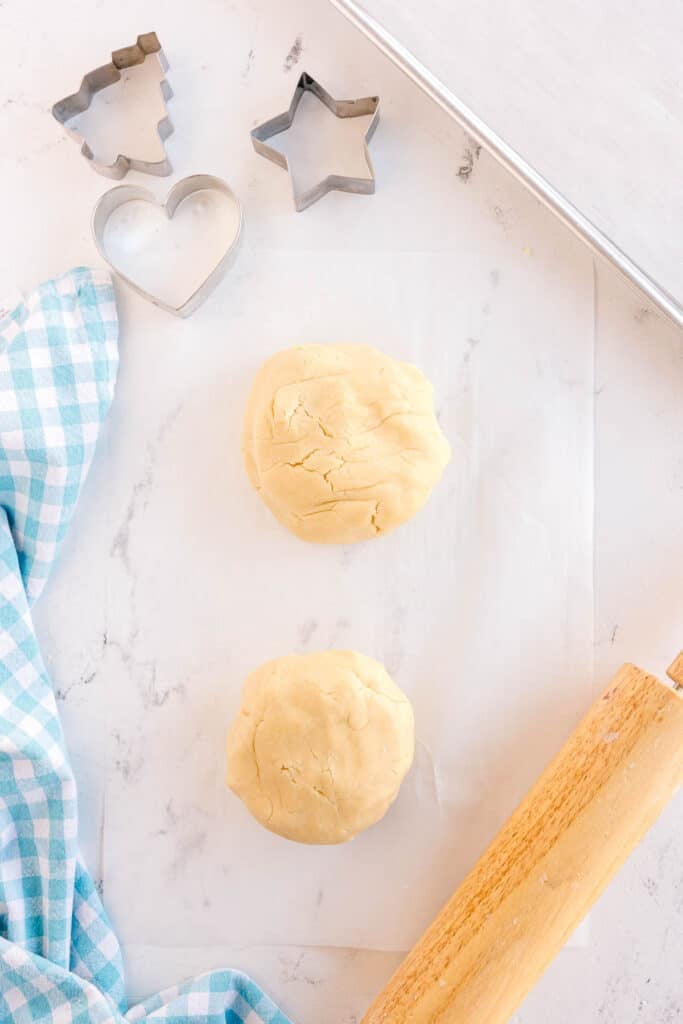 Two balls of sugar cookie dough on parchment paper.