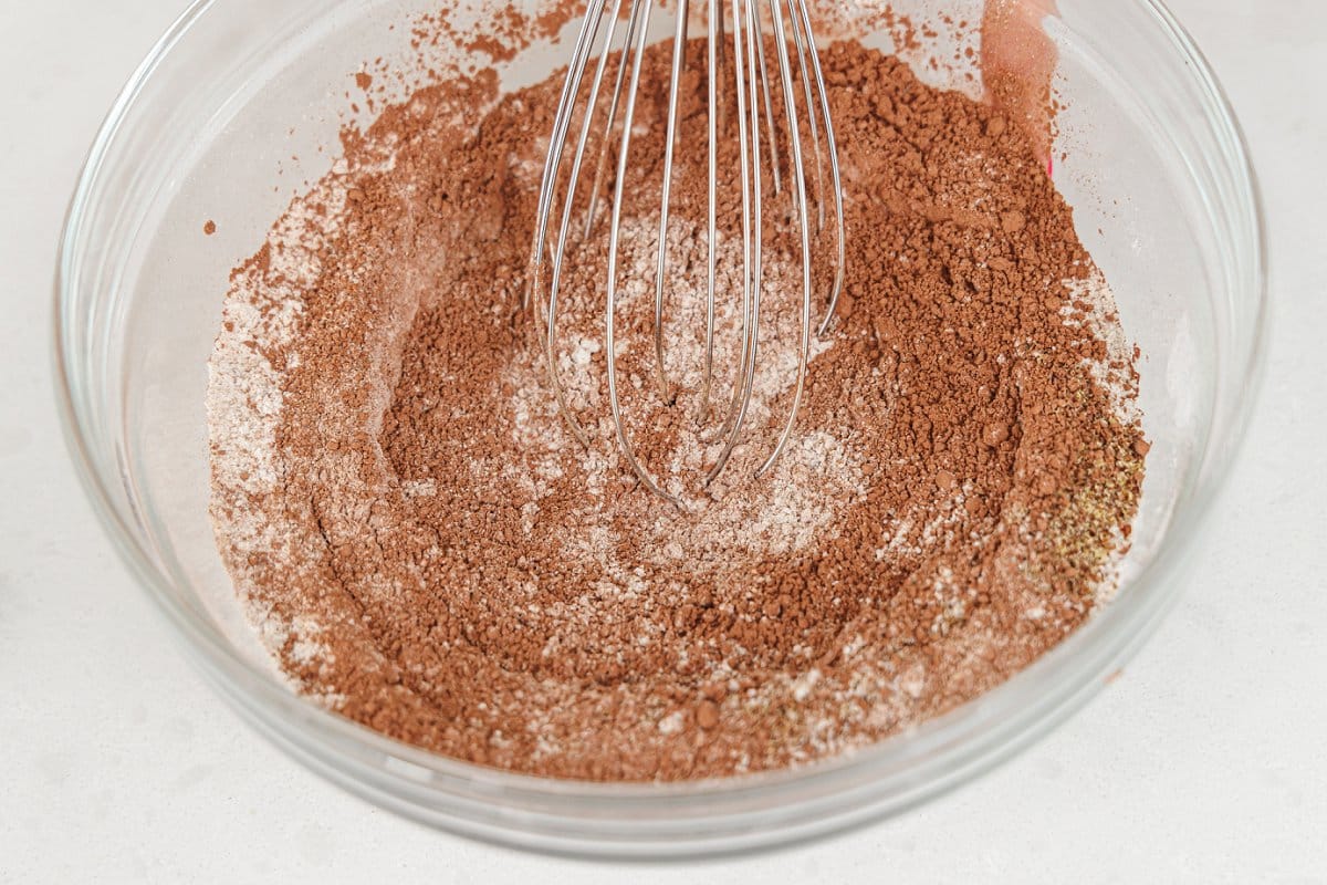 Whisking dry ingredients for bread in a large glass bowl.