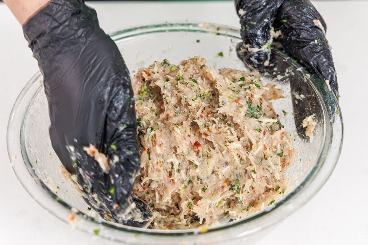 Hand mixing meatloaf ingredients into one.