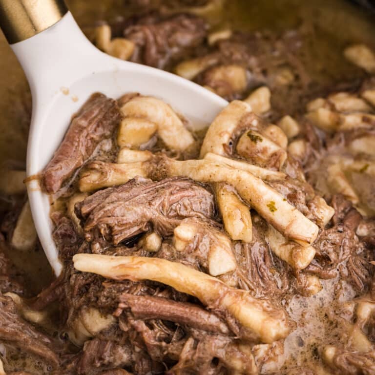 spoon scooping beef and noodles from a crockpot.