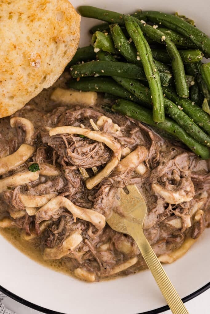 closeup of a plate of beef & noodles with green beans.