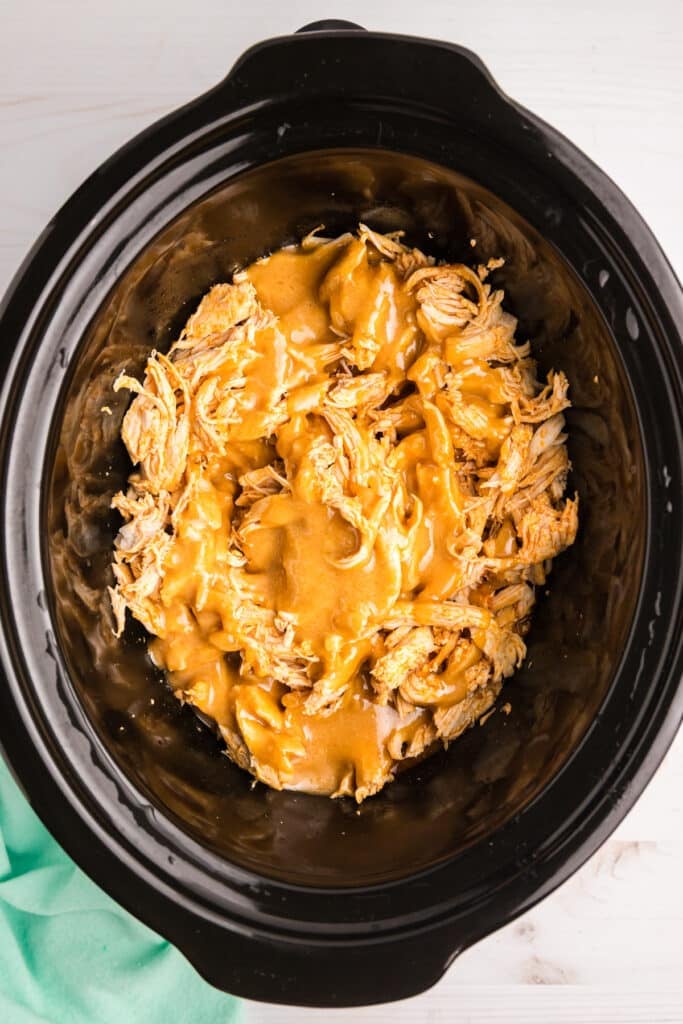 sauce poured over shredded chicken in a crockpot.