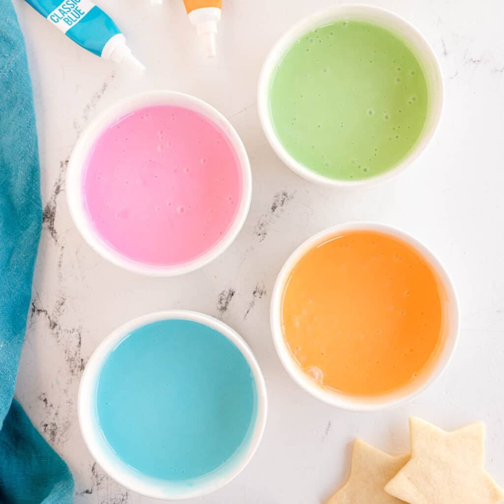 Four bowls of colorful cookie icing.