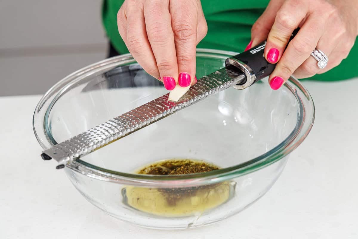 Grating garlic into a glass bowl.