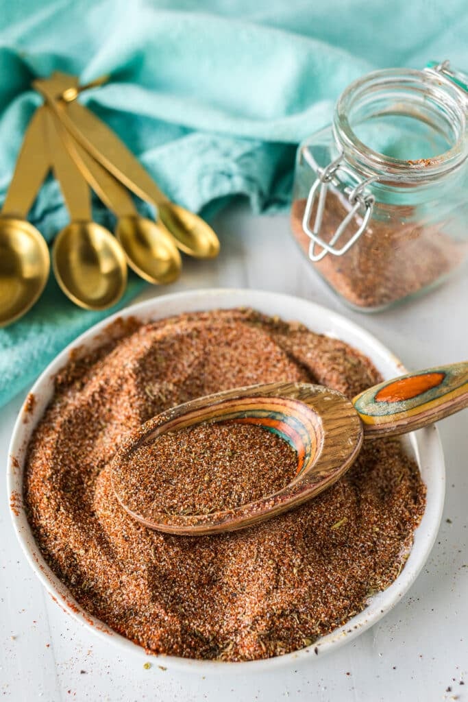 homemade blackened seasoning on a plate with a wooden scoop.